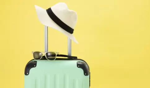 top-view-of-suitcase-sunglasses-camera-and-hat-on-yellow-background-vacation-concept